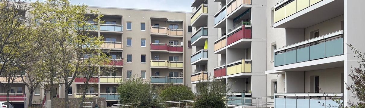 Modernisierte Mehrfamilienhäuser mit farbigen Balkonen, begrüntem Innenhof und barrierefreien Wegen