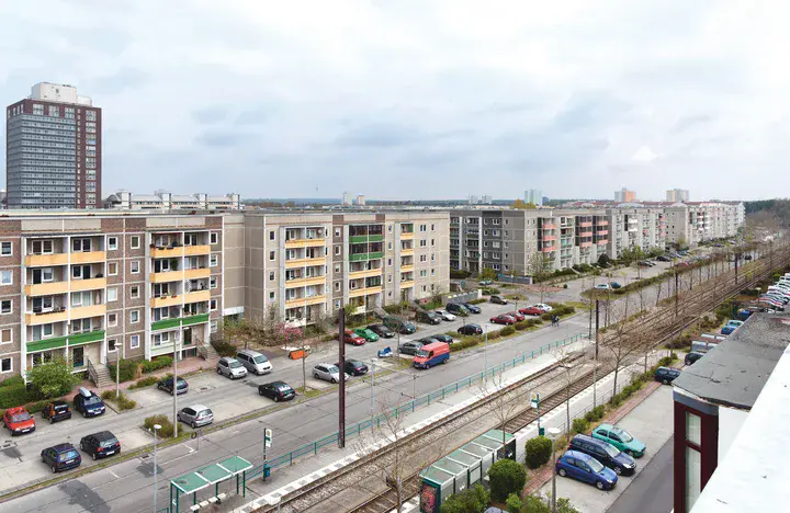Eine lange Straße mit vielen Autos vor zahlreichen Wohnhäusern.