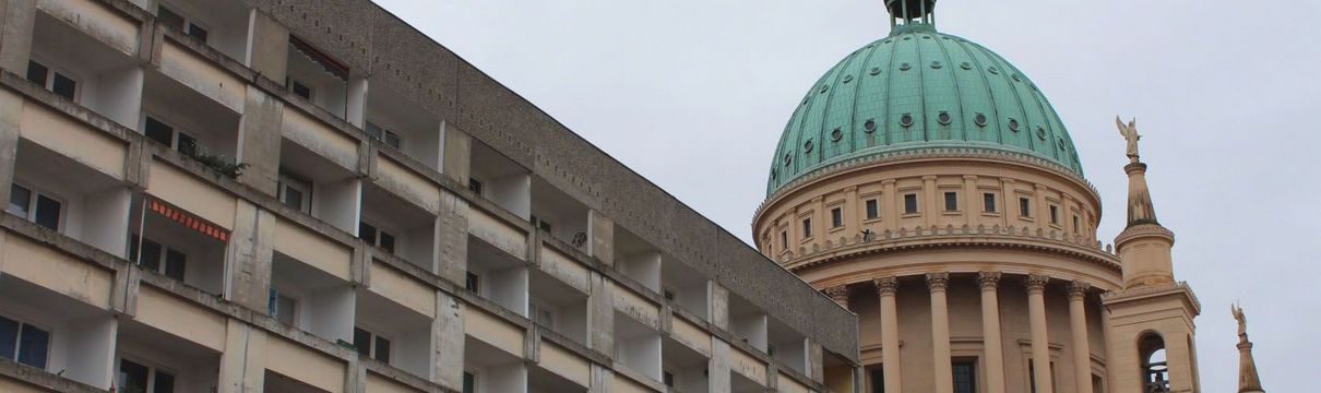 Ein fünfstöcikger Plattenbau mit der Potsdamer Nikolaikirche im Hintergrund