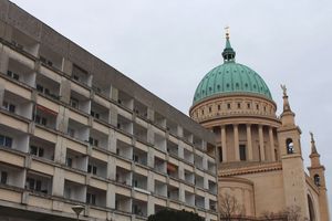 Ein fünfstöcikger Plattenbau mit der Potsdamer Nikolaikirche im Hintergrund