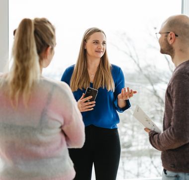Drei Personen im Gespräch vor einer Glaswand