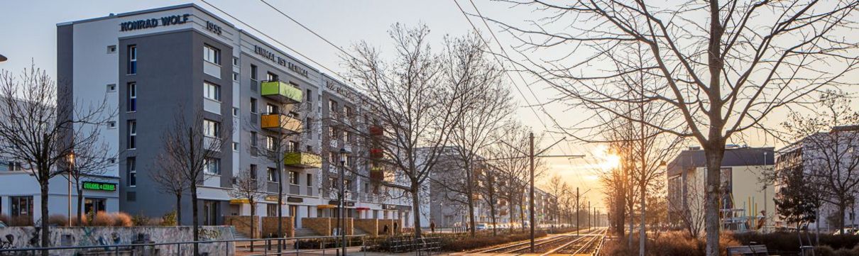 Die sanierte Rolle in der Konrad-Wolf-Allee in Drewitz mit Blick über den begrünten Mittelstreifen und Straßenbahnschienen im Abendlicht