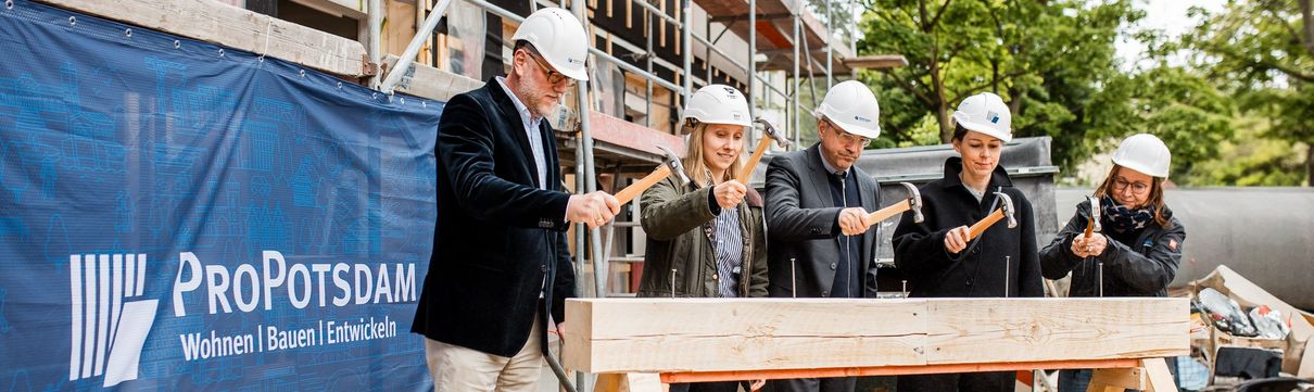 Traditionelles Nageleinschlagen beim Richtfest im Potsdamer Patrizierweg mit fünf Menschen.